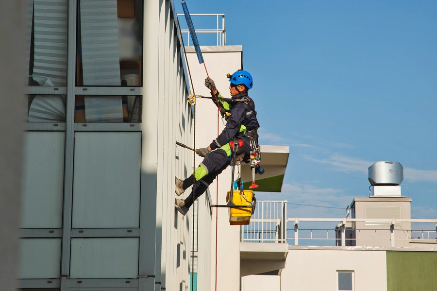 Equipe em acesso por corda na fachada de edifício